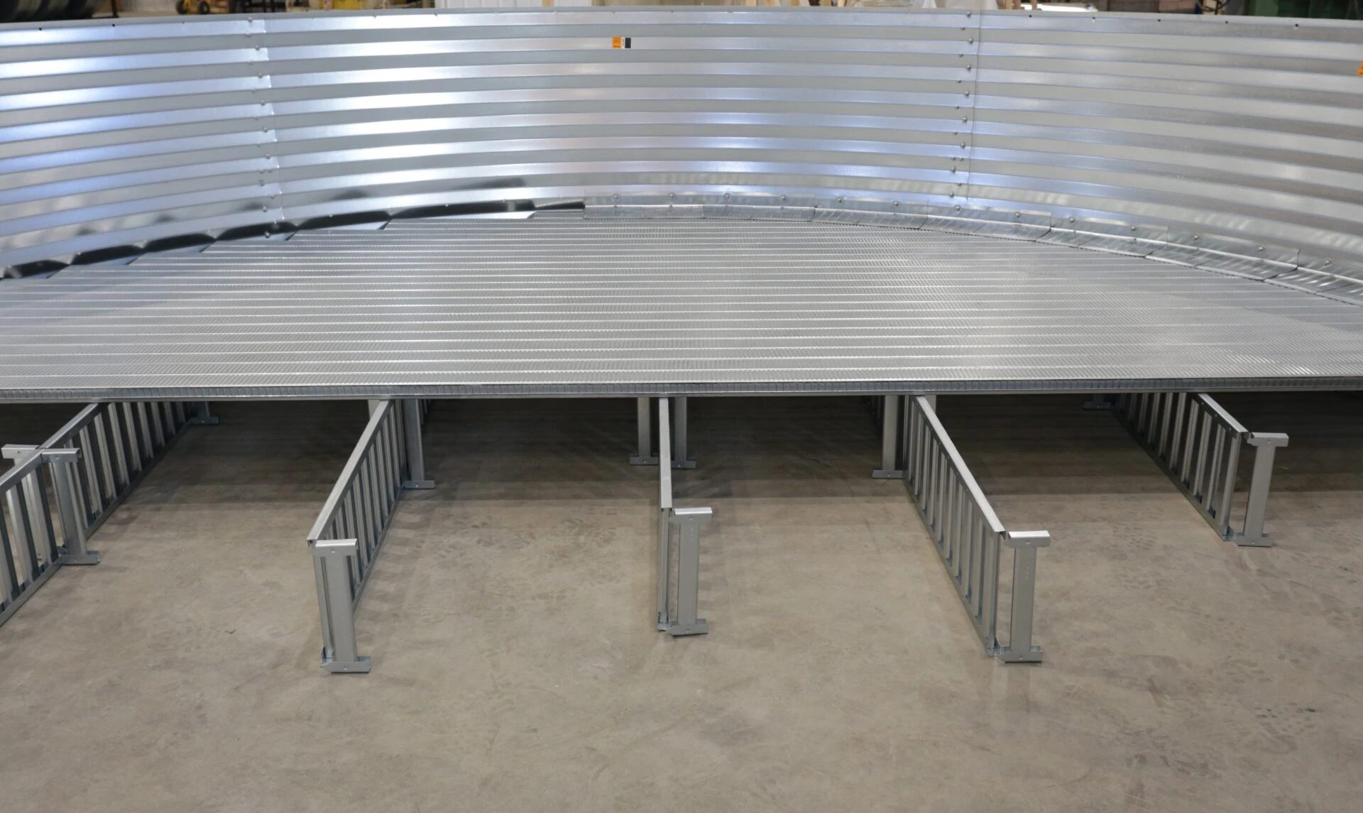 Close-up of a galvanized metal structure with curved walls and a fenced area, showcasing industrial design and robust construction